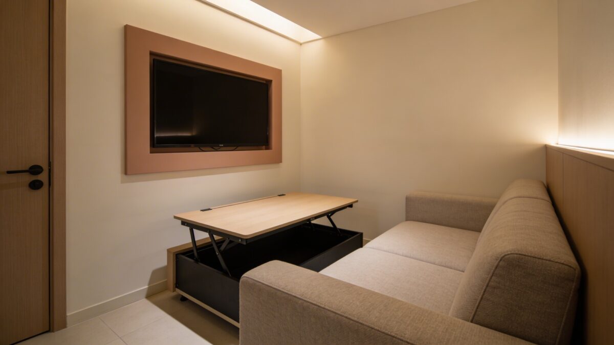 A stylish small living room showing a lift-top coffee table next to a sofa, with the TV mounted high on the wall and a wall color that echoes the TV frame, creating a cohesive, seamless look.