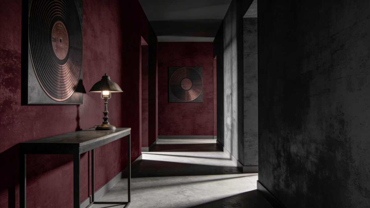 Moody and dramatic hallway wallpaper: textural lamp-inspired album cover motifs, deep burgundy and charcoal tones, moody chiaroscuro lighting, a minimalist console table with a vintage lamp casting long shadows.
