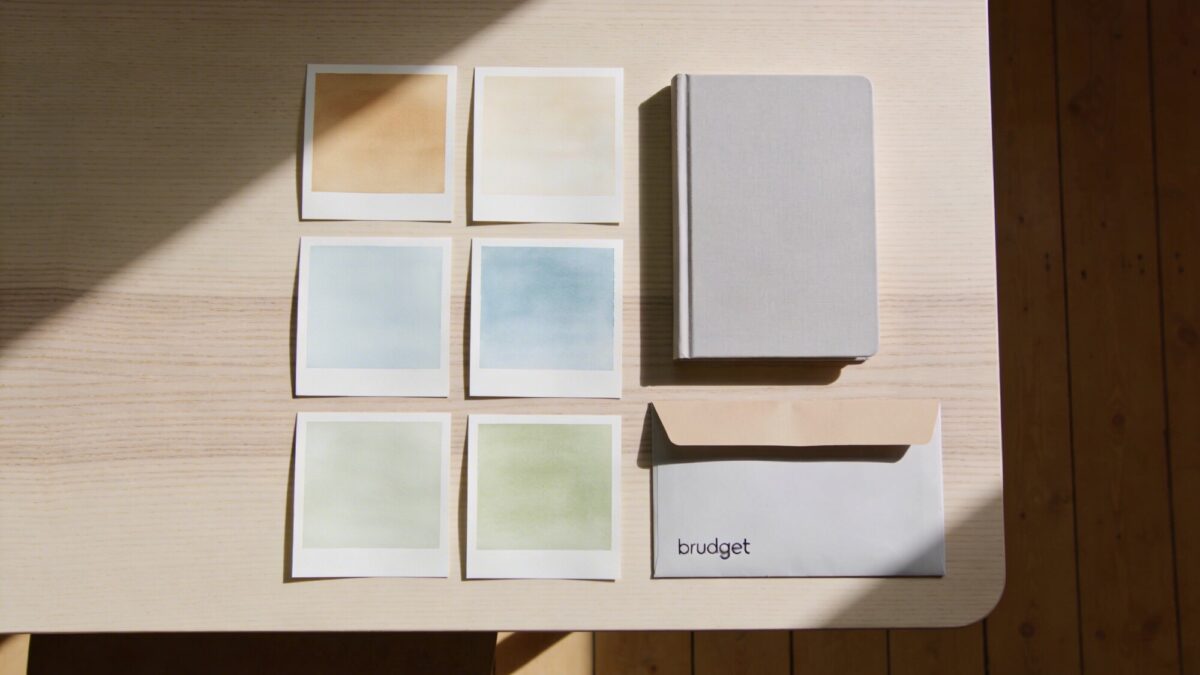 A minimalist kitchen color mood board on a table with paint swatches, a small notebook listing top three goals, and a budget envelope to convey planning without text on the image.
